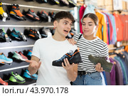 Guy with girlfriend, view specialized shoes in store, near showcase with summer trecking cross-shoes. Стоковое фото, фотограф Яков Филимонов / Фотобанк Лори