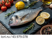Delicious and healthy fish. Raw dorado with lemon and ingredients on a dark background. Banner, menu, place for recipe text, top view. Стоковое AI-изображение, AI-художник Photojuli / Фотобанк Лори