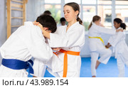 Teenage girl performing knee strike to boy in sparring during jiu-jitsu class. Стоковое фото, фотограф Яков Филимонов / Фотобанк Лори