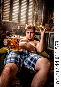 Fat man eating a hamburger sitting on a chair in the slums. Стоковое фото, фотограф Андрей Армягов / Фотобанк Лори