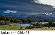 Beautiful autumn landscape. A forest grows on the shore of a calm lake. The path winds through a meadow with yellowed grass. Mountains against a background of blue sky and clouds. Lapataia Bay. Стоковое фото, фотограф Вера Ивановна Кубарева / Фотобанк Лори