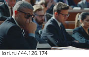 Concerned witness wearing sunglasses listening to testimony in courtroom. Стоковое AI-видео, аниматор Данил Руденко / Фотобанк Лори