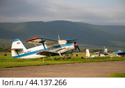 Самолет Ан-2 на стоянке аэродрома на фоне сопок (2024 год). Редакционное фото, фотограф Павел Сапрыкин / Фотобанк Лори