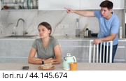 Upset young woman sitting at the kitchen-table with her back to her husband disputing with her. Стоковое видео, видеограф Яков Филимонов / Фотобанк Лори