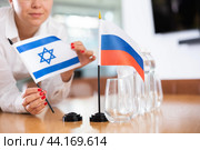 Unrecognizable girl sets midget flags of Russia and Israel before international negotiations. Стоковое фото, фотограф Яков Филимонов / Фотобанк Лори