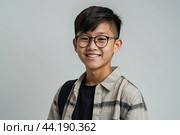 Portrait of a happy Asian schoolboy teenager with glasses on a solid gray background. Back to school, correction of pupil kid eyesight. AI generated. Стоковое AI-изображение, AI-художник Ольга Симонова / Фотобанк Лори