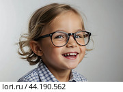 Portrait of a happy Caucasian kid preschooler with glasses on a solid gray background. Back to school, correction of pupil kid eyesight. AI generated. Стоковое AI-изображение, AI-художник Ольга Симонова / Фотобанк Лори