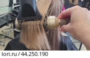 A hairdresser straightening hair with a hairdryer, the work process close-up. Стоковое видео, видеограф Сергей Чайко / Фотобанк Лори