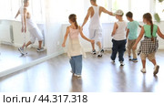 Happy young girl and boy in casual clothes performing hip hop dance in dancing room during training with male teacher. Стоковое видео, видеограф Яков Филимонов / Фотобанк Лори