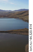 Vertical drone video of flying over a hilly rural landscape with a winding road and fish ponds. Altai Krai. Стоковое видео, видеограф Сергей Пристяжнюк (Serg Zastavkin) / Фотобанк Лори