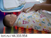 Женина учится пеленать новорожденного ребенка на стенде на тему медицины будущего в Гостином дворе в рамках форума-фестиваля "Территория будущего. Москва 2030" в городе Москве, Россия (2024 год). Редакционное фото, фотограф Николай Винокуров / Фотобанк Лори