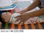 Женина учится пеленать новорожденного ребенка на стенде на тему медицины будущего в Гостином дворе в рамках форума-фестиваля "Территория будущего. Москва 2030" в городе Москве, Россия (2024 год). Редакционное фото, фотограф Николай Винокуров / Фотобанк Лори