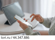Woman working from home with tablet and phone. Woman hands with cellphone. Cropped shot view of woman hands holding mobile phone with contacts. Стоковое фото, фотограф Павел Муравьев / Фотобанк Лори