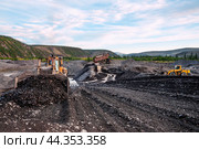 Американский бульдозер CATERPILLAR в горной местности, сгребает от промывочного устройства отработанный горный грунт, чтобы затем его сгрести ковшом в отвал. На дальнем плане - стационарное промывочное устройство для промывки золота (2010 год). Редакционное фото, фотограф Павел Просянов / Фотобанк Лори