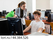 Frustrated teacher talking to neglectful teenage student in computer class. Стоковое фото, фотограф Яков Филимонов / Фотобанк Лори