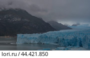 An incredible glacier stretches to the horizon between the mountains. A mass of blue ice with cracks and sharp peaks. Thawed ice floes float in a glacial lake. Cloudy. Fog. Perito Moreno. El Calafate. Стоковое фото, фотограф Вера Ивановна Кубарева / Фотобанк Лори