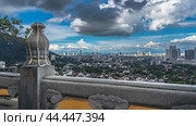 The panorama of the city is visible from the observation deck of the Chinese temple. Buildings among the trees. Skyscrapers against a blue sky, clouds.There is a carved stone railing in the foreground (2023 год). Стоковое фото, фотограф Вера Ивановна Кубарева / Фотобанк Лори