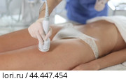 Aesthetician administering hardware procedure on female patient in cosmetology clinic, using ice hammer attachment to reduce body fat and contour thighs. Стоковое видео, видеограф Яков Филимонов / Фотобанк Лори