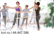 In ballet studio bathed in natural light, group of everyday women of different ages learning demi rond de jambe under guidance of female choreographer in beginners class. Стоковое видео, видеограф Яков Филимонов / Фотобанк Лори