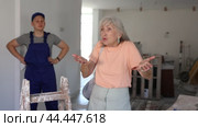 Portrait of disgruntled teenager construction worker and annoyed gesturing woman in house being renovated. Boy having conflict with client during summer internship. Стоковое видео, видеограф Яков Филимонов / Фотобанк Лори