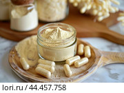 Maca root powder and capsules on wooden plate. Стоковое AI-изображение, AI-художник Иван Рябоконь / Фотобанк Лори