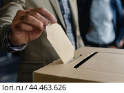 Voter casting ballot in box at polling station. Стоковое AI-изображение, AI-художник Иван Рябоконь / Фотобанк Лори