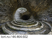 Wideangle view inside an old circular stone amphitheater with concentric stairs. Стоковое AI-изображение, AI-художник Иван Рябоконь / Фотобанк Лори