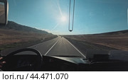 An interior view of a moving vehicle on a desert road with one hand on the steering wheel. Стоковое видео, видеограф Ярославский Максим / Фотобанк Лори