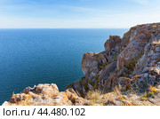 Baikal Lake on sunny autumn day. View from coastal rocks covered with red lichens and mosses to endless expanse of blue water of lake in October. Travels and hikes in Tazheran steppe and coast of Baikal. Стоковое фото, фотограф Виктория Катьянова / Фотобанк Лори