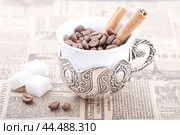 Чашка белого кофе, наполненная кофейными зернами и палочками корицы (2014 год). Редакционное фото, фотограф Александр Рыбалка / Фотобанк Лори
