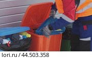 Waste management worker sorting recyclables in colorful bins at a municipal facility in the afternoon. Стоковое видео, видеограф Сергей Толмачёв / Фотобанк Лори