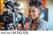 Young black woman videographer smiling while operating camera on set. Стоковое AI-изображение, AI-художник Юрий Поздников / Фотобанк Лори