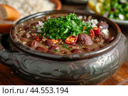 Hearty feijoada stew with rice garnished with fresh parsley, a brazilian cuisine classic. Стоковое AI-изображение, AI-художник Иван Рябоконь / Фотобанк Лори