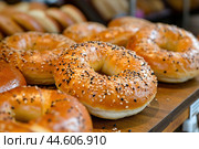Freshly baked seeded bagels on display. Стоковое AI-изображение, AI-художник Иван Рябоконь / Фотобанк Лори