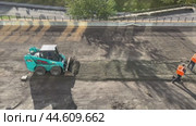 IRKUTSK, RUSSIA - September 06, 2024: Video of a team of road workers in orange vests prepares soil for laying paving slabs on a road under repair. One worker brings gravel and sand in a loader. Редакционное видео, видеограф Виктория Катьянова / Фотобанк Лори