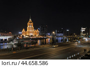 Ночной вид на здание отеля Radisson Collection Moscow, Москву-реку, Краснопресненскую набережную. По реке проплывает большой теплоход. Ночные огни города. Светящиеся окна зданий.  Уличное вечернее освещение. Редакционное фото, фотограф Сергей Никифоров-Гордеев / Фотобанк Лори