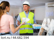 Woman owner of apartment giving wage to man construction painter. Стоковое фото, фотограф Яков Филимонов / Фотобанк Лори