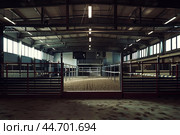 Empty indoor horse riding arena with sand and fences. Стоковое AI-изображение, AI-художник Иван Рябоконь / Фотобанк Лори