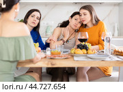 Sad Spanish woman sits silently in kitchen, female friends sympathize and comfort woman. Стоковое фото, фотограф Яков Филимонов / Фотобанк Лори