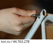 Closeup of a hand screwing Allen key. Furniture assembling. Two parts (pipe and shelf) are screw together to get the bookcase. Using the hex wrench. Стоковое фото, фотограф YuryKara / Фотобанк Лори