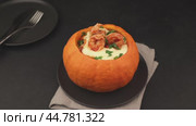 Whole baked pumpkin with tiger prawns, melted cheese and tomatoes. A woman opens a pumpkin. Traditional dish of Brazil, home cooking. Selective focus, close-up, black background. Стоковое видео, видеограф Наталья Любина / Фотобанк Лори