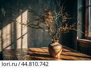 Branches with golden autumn leaves in a ceramic vase on a wooden table by the window. The concept of home comfort. Autumn decor for Halloween. Стоковое AI-изображение, AI-художник Photojuli / Фотобанк Лори
