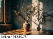 Branches with golden autumn leaves in a ceramic vase on a wooden table by the window. The concept of home comfort. Autumn decor for Halloween. Стоковое AI-изображение, AI-художник Photojuli / Фотобанк Лори