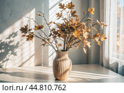 Branches with golden autumn leaves in a ceramic vase on a wooden table by the window. The concept of home comfort. Autumn decor for Halloween. Стоковое AI-изображение, AI-художник Photojuli / Фотобанк Лори