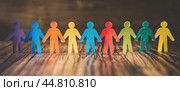 A chain of colorful men cut out of paper on a wooden table symbolizes the support of the community and friendship of people. Стоковое AI-изображение, AI-художник Ярославский Максим / Фотобанк Лори
