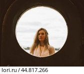 The face of young girl in round frame window on background of sea, ocean, on waterfront. Portrait in circle, backlit. Стоковое фото, фотограф Natalia Gdovskaia / Фотобанк Лори