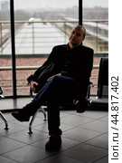 Train Station. A mature man in business clothes and a coat is sitting in a waiting room. Стоковое фото, фотограф Natalia Gdovskaia / Фотобанк Лори