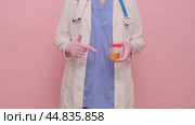 Doctor hand holds a container for taking a urine test for virus, studio pink background. Hand in a medical glove with a jar for testing for the flu virus. Стоковое видео, видеограф Андрей Журавлев / Фотобанк Лори