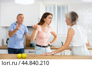 Elderly father tries to calm quarreled wife and daughter in home kitchen. Стоковое фото, фотограф Яков Филимонов / Фотобанк Лори