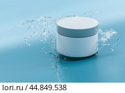 White, blank, unbranded cosmetic cream jar and water on blue background. Skin care product presentation. Elegant mockup. Skincare, beauty and spa. Jar with copy space. 3D rendering. Стоковое фото, фотограф Павел Муравьев / Фотобанк Лори
